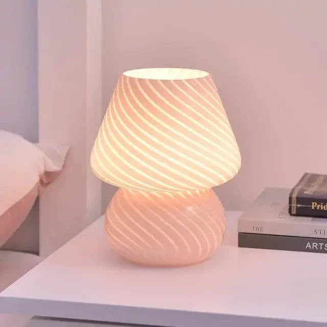 Mushroom LED Lamp made of clear glass with a white spiral stripe pattern, emitting warm light, placed on a white table