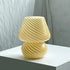 Mushroom LED Lamp made of clear hand-blown glass with white spiral stripes and a round base, emitting soft warm light