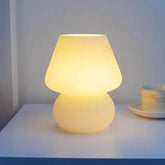 Mushroom LED Lamp with a warm yellow glass body and dome-shaped shade emitting soft ambient light on a white surface