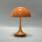 Portable Rechargeable LED Lamp in orange with glossy finish, dome-shaped metal shade, and sleek curved base