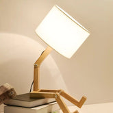 Robot Table Lamp with white fabric shade and wooden adjustable articulated arm resembling a robot figure sitting pose