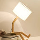 Robot Table Lamp with white fabric shade and wooden adjustable articulated arm resembling a robot figure sitting pose