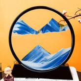 Sand Frame with black circular acrylic frame displaying blue and white textured sand art resembling mountains
