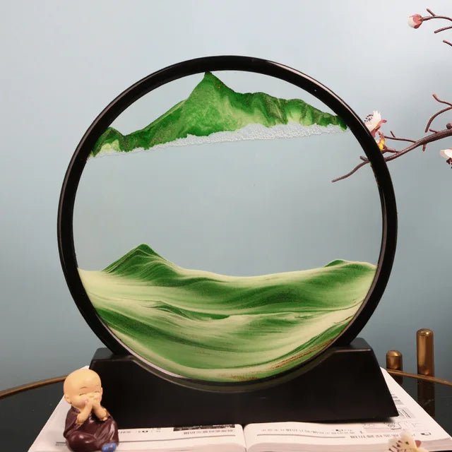 Sand Frame with black circular acrylic frame displaying layered green and white sand forming mountain and landscape patterns