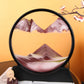 Sand Frame with black circular acrylic frame containing layered red, white, and green fine sand creating a textured mountain landscape design