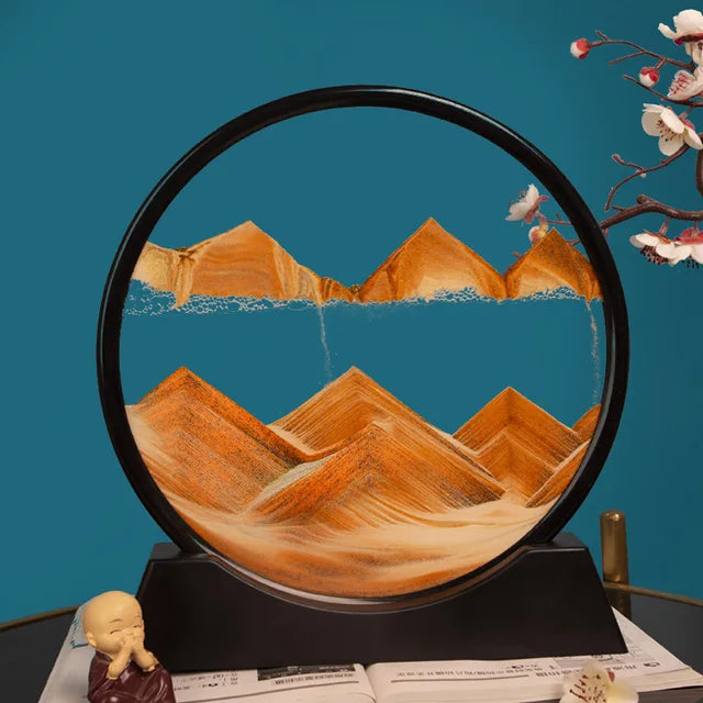 Sand Frame with black circular acrylic frame containing flowing orange sand forming mountain patterns against a blue background