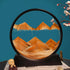 Sand Frame with black circular acrylic frame containing flowing orange sand forming mountain patterns against a blue background