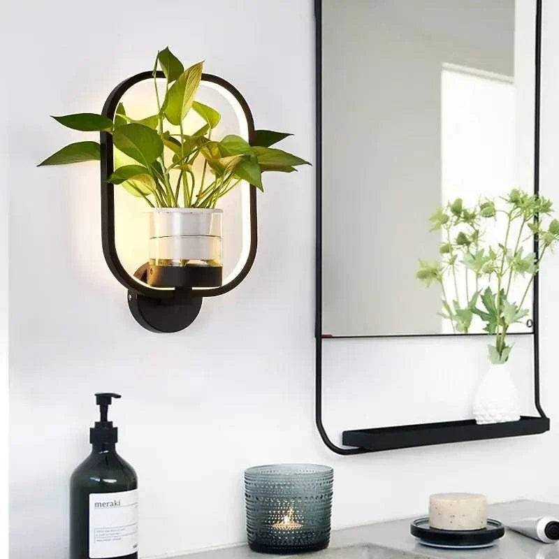Wall Plant LED Lamp featuring black oval frame with integrated LED lighting and a white cylindrical plant pot holding green leafy plants