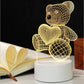 3D LED Lamp shaped like a teddy bear holding a heart, featuring a yellow optical illusion wireframe design on a white base