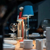 Cordless lamp with a sleek metal stem and blue fabric shade, designed for versatile indoor and outdoor lighting.