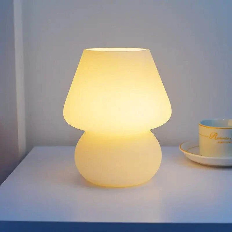 Mushroom LED Lamp with warm yellow glass shade and rounded base emitting soft glow on white surface