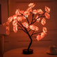 Rose Tree Lamp with warm glowing pink resin flower petals and black metal branches on a round base